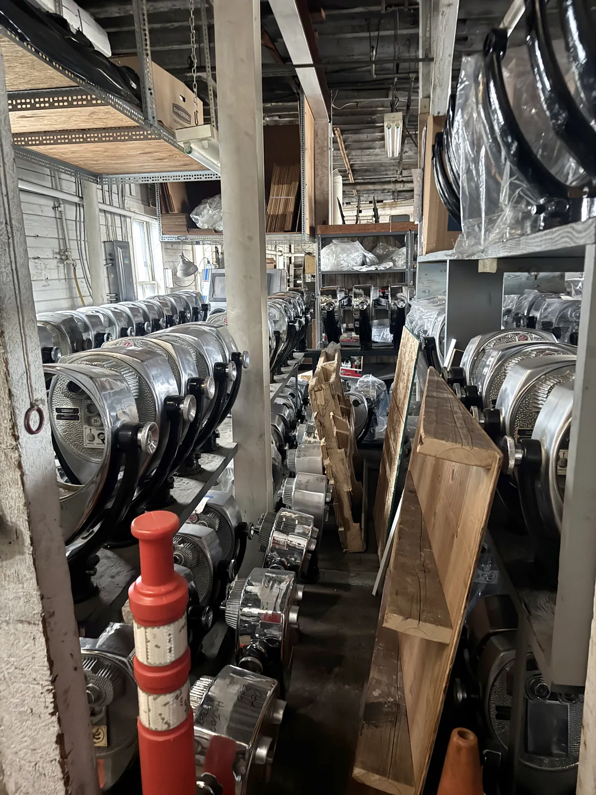 An aisle between racks of refurbished chrome viewer heads in the Norwalk shop